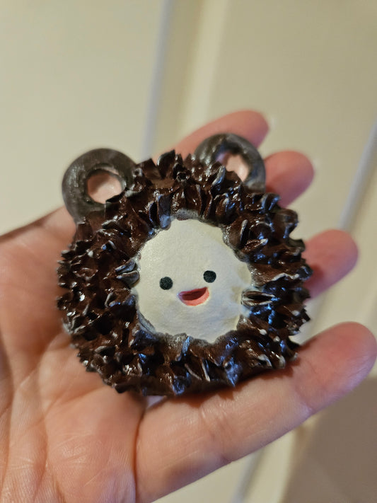 Hand holding an AngeLouise Ceramics Potato Pal that is wearing a brown furry onesie with ears, all made from ceramics. 